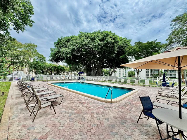 a view of swimming pool with chairs and trees