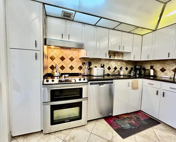 a kitchen with granite countertop a stove a sink and a refrigerator