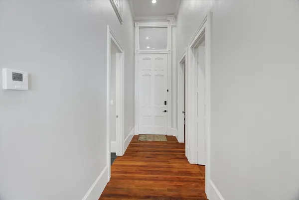 a view of a hallway with wooden floor and a bathroom