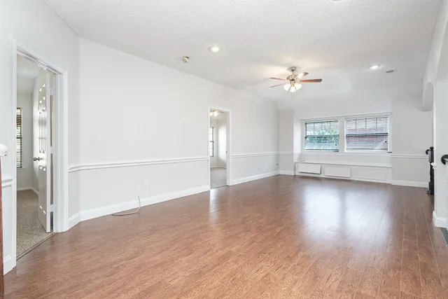 a view of empty room with wooden floor and ceiling fan