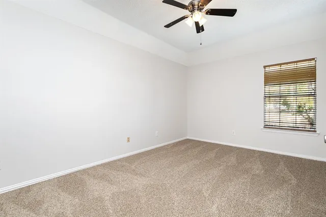 an empty room with a window and a ceiling fan