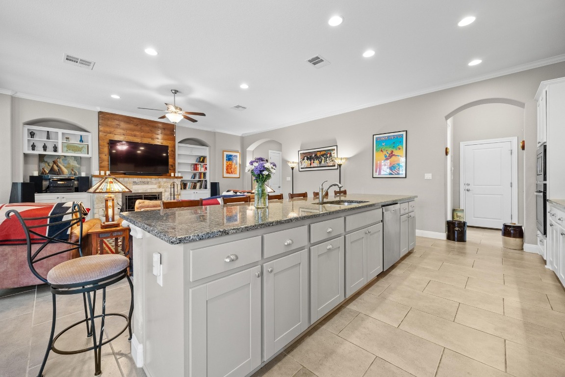 a large kitchen with stainless steel appliances granite countertop a sink and a white cabinets
