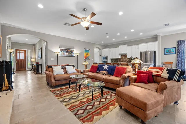 a living room with furniture kitchen view and a chandelier