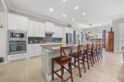 a kitchen with stainless steel appliances a table chairs sink and cabinets