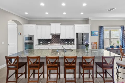 a kitchen with stainless steel appliances a table chairs sink and cabinets