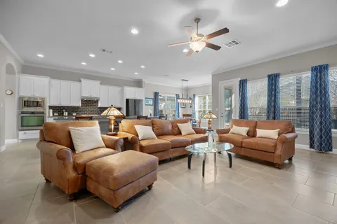 a living room with furniture kitchen view and a chandelier