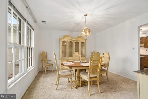 a view of a dining room with furniture a chandelier and a window