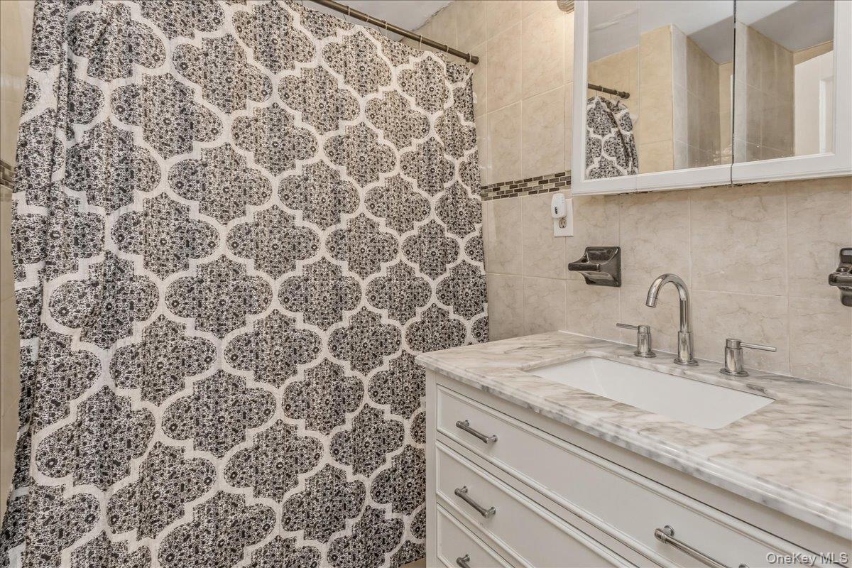 237 Rhodes Avenue Hempstead, NY 11550 - Photo 15 of 24 a bathroom with a granite countertop sink a mirror and shower
