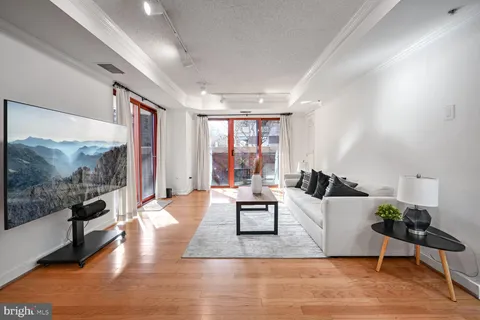 a living room with furniture large window and wooden floor