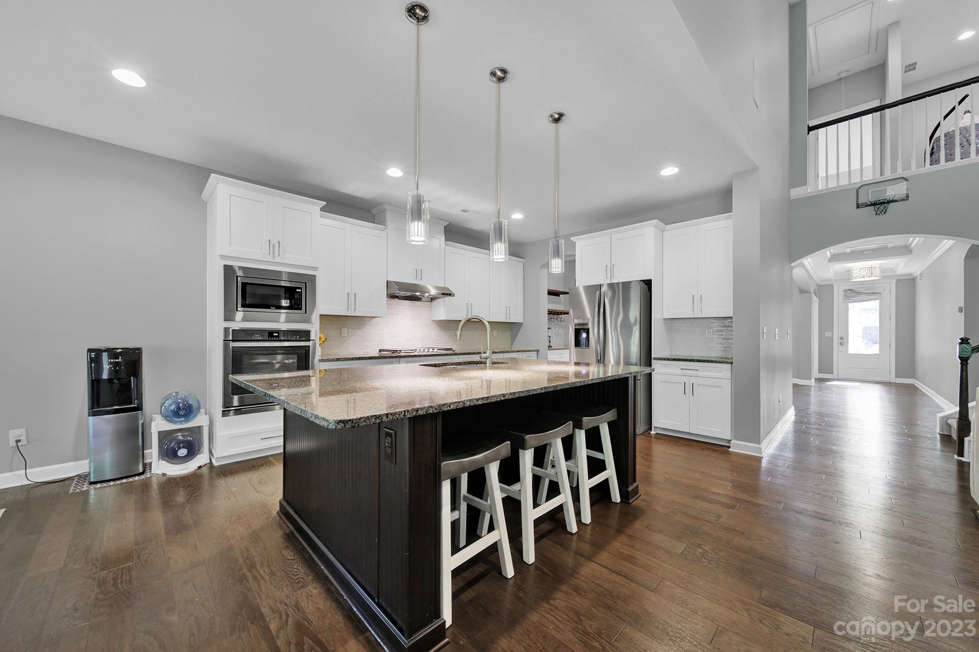 1516 Hazel Street Tega Cay, SC 29708 - Photo 16 of 48 a kitchen with stainless steel appliances granite countertop a kitchen island a stove a refrigerator a oven a sink a dining table and chairs with wooden floor