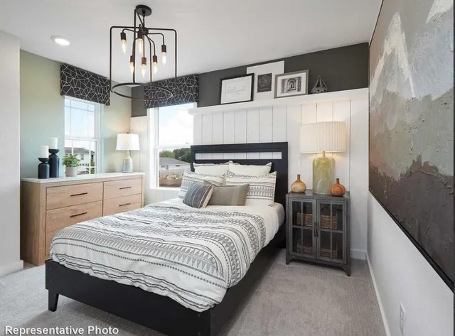 a bedroom with a bed a chandelier and dresser