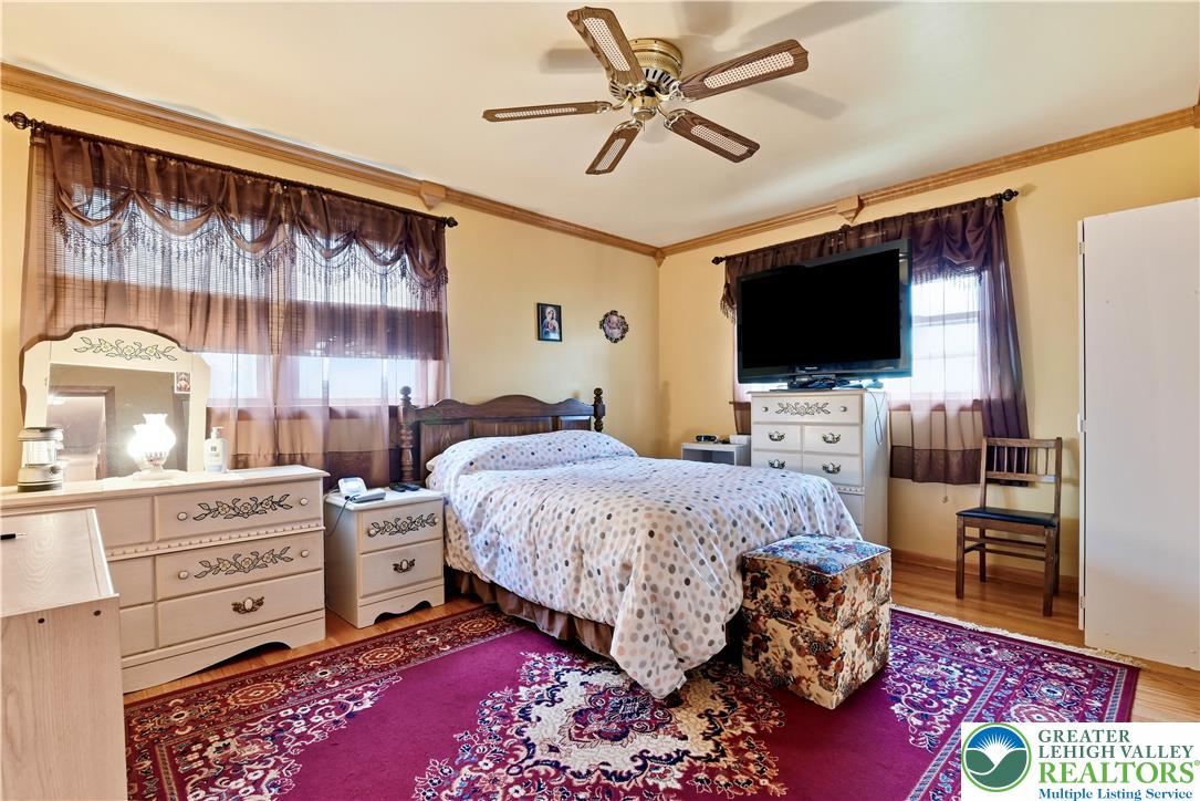 3303 Barklay Road Whitehall, PA 18052 - Photo 25 of 39 A comforting bedroom features warm walls, rich wood flooring, and a decorative ceiling fan, creating a welcoming atmosphere.