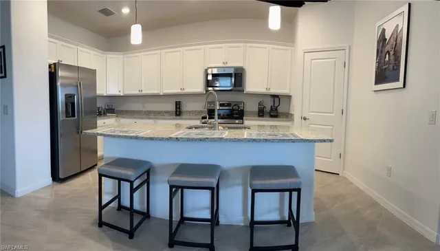 a kitchen with stainless steel appliances granite countertop a table chairs microwave and sink