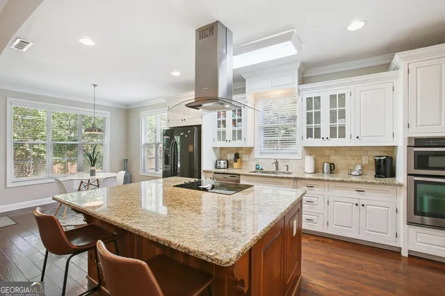 a kitchen with stainless steel appliances a dining table chairs refrigerator and sink