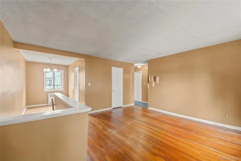 a view of an empty room with window and wooden floor