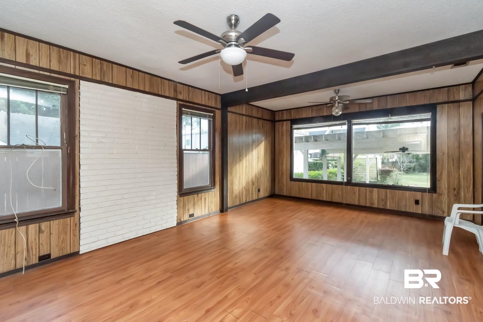 4305 Stein Street Mobile, AL 36608 - Photo 12 of 22 Unfurnished room with brick wall, ceiling fan, wooden walls, wood-type flooring, and beamed ceiling