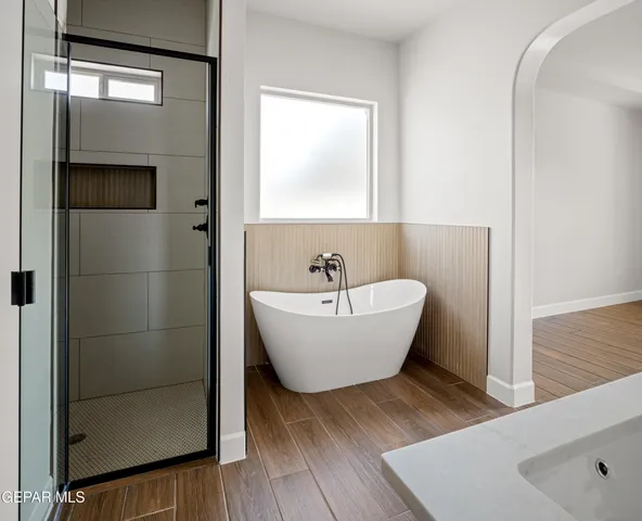 a bathroom with a white tub shower sink and mirror