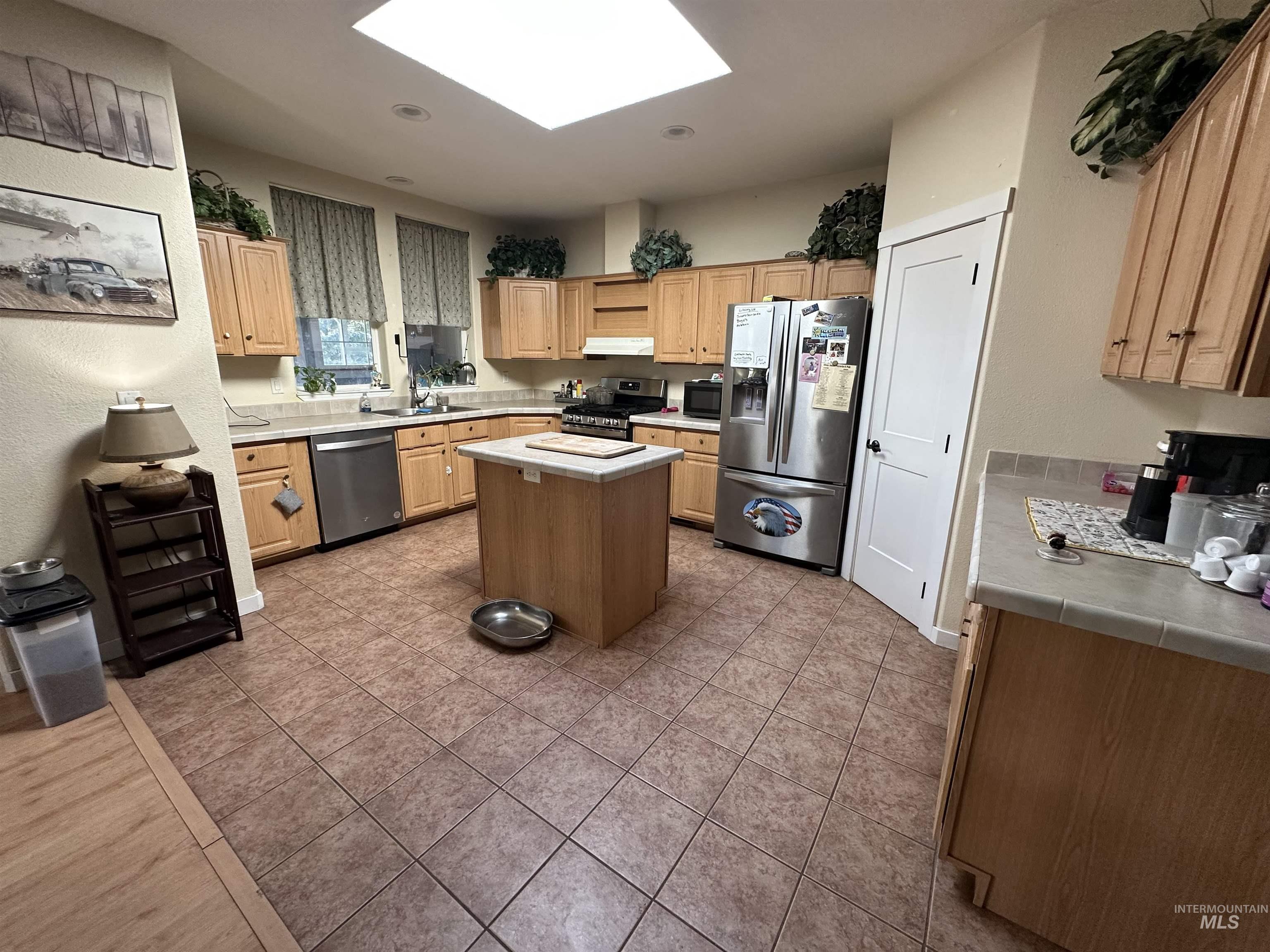 2859 Luke's Gulch Road Stites, ID 83552 - Photo 14 of 48 Kitchen featuring a skylight, a center island, stainless steel appliances, dark tile patterned floors, and light wood finish cabinets