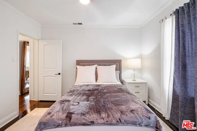 a bedroom with a large bed and a wooden floor