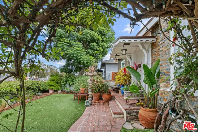 a view of a patio with table and chairs potted plants and large tree