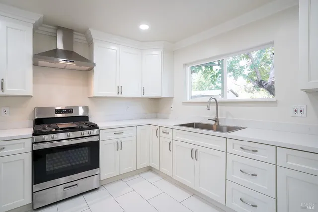 a kitchen with granite countertop white cabinets stainless steel appliances and a large window