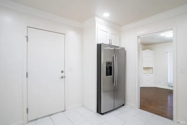 a view of a refrigerator in kitchen and an empty room