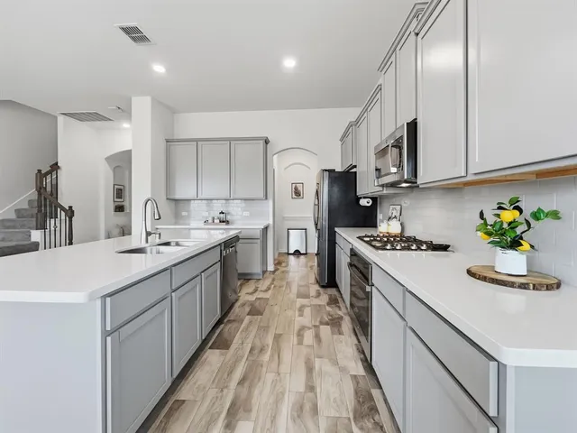 a kitchen with stainless steel appliances granite countertop a sink a stove and a refrigerator