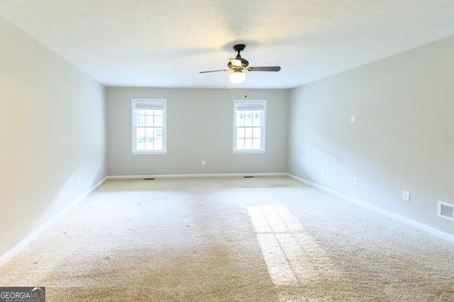 an empty room with fan and windows