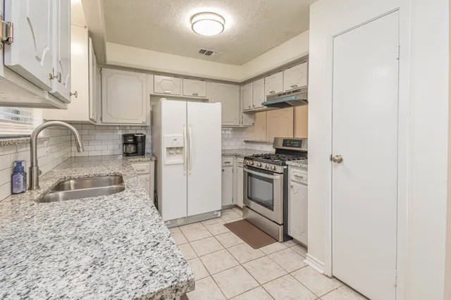 a kitchen with granite countertop a refrigerator stove and sink