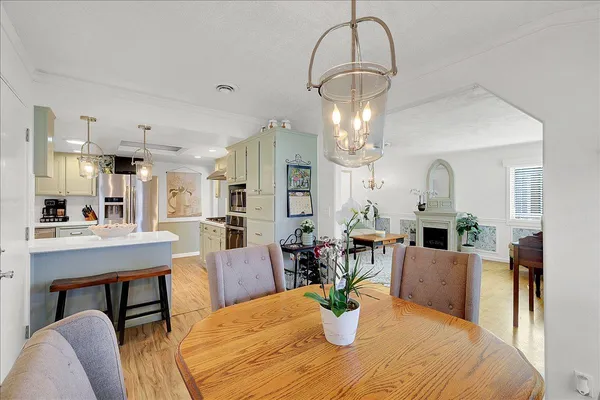 a dining room with wooden floor a chandelier a wooden table and chairs