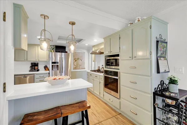 a kitchen with stainless steel appliances kitchen island granite countertop a table chairs and a refrigerator