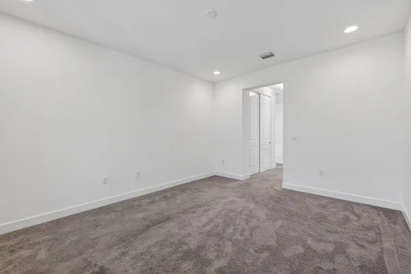 a view of an empty room with window and chandelier fan