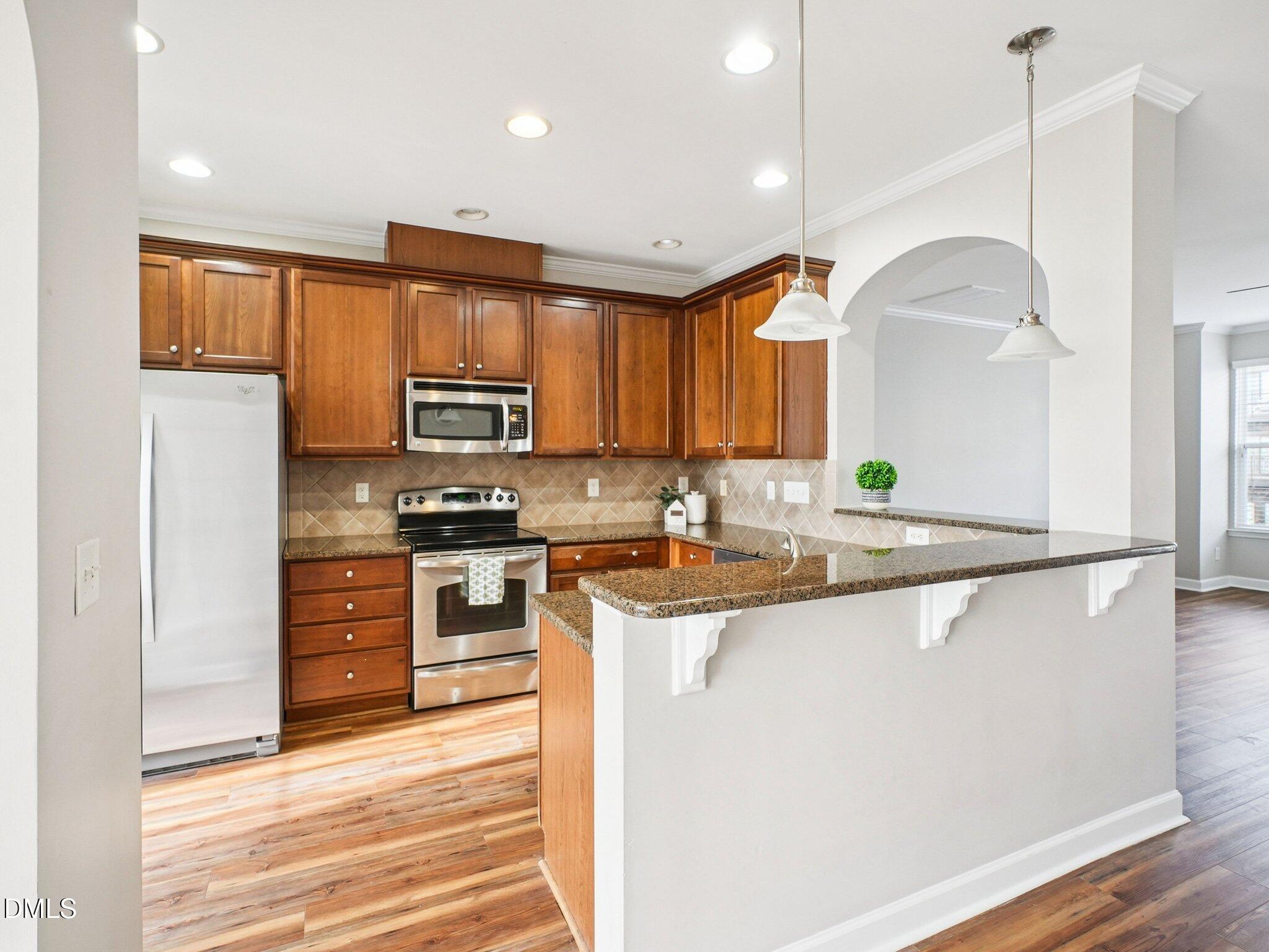9238 Wooden Road Raleigh, NC 27617 - Photo 17 of 45 a kitchen with stainless steel appliances granite countertop a sink a stove and a refrigerator