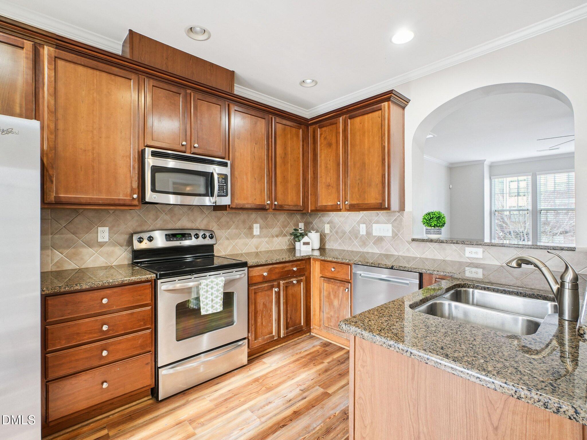 9238 Wooden Road Raleigh, NC 27617 - Photo 18 of 45 a kitchen with granite countertop stainless steel appliances a stove sink and cabinets