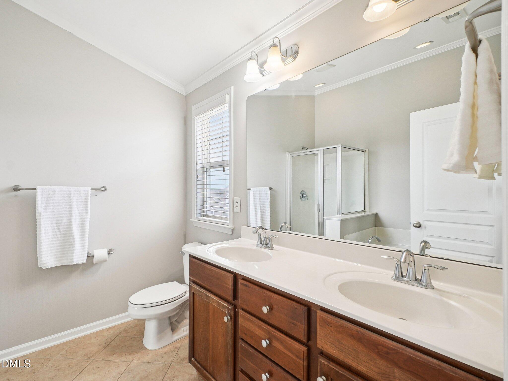 9238 Wooden Road Raleigh, NC 27617 - Photo 30 of 45 a bathroom with a double vanity sink toilet and a mirror