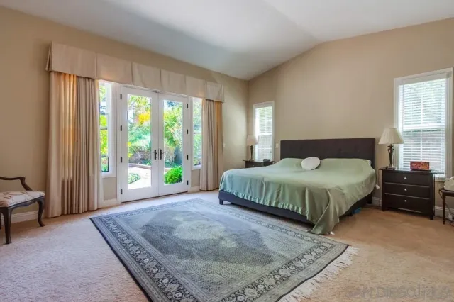 a bedroom with a bed and large windows