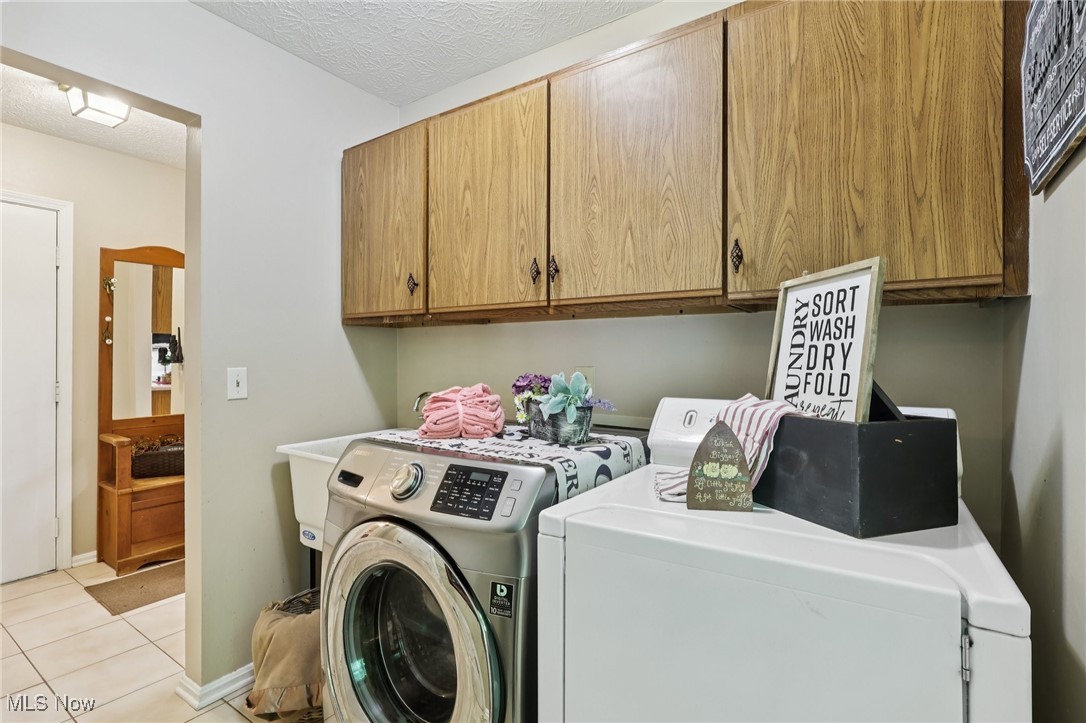 5568 Forest Glen Road Madison, OH 44057 - Photo 36 of 50 Laundry room with independent washer and dryer, cabinet space, light tile patterned flooring, and a textured ceiling