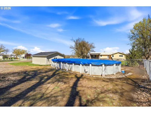 a view of backyard with large tree and wooden fence