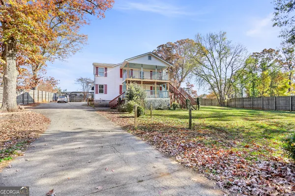 a view of a white house with a yard and large tree