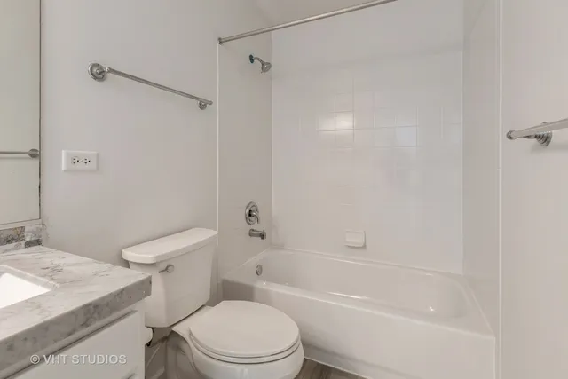 a white toilet and tub sitting next to a bathroom sink