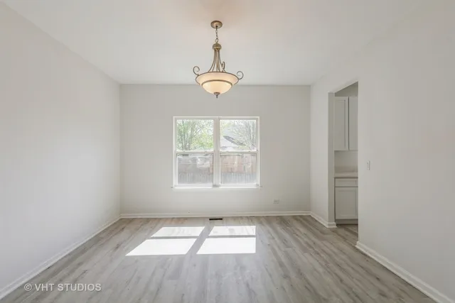 an empty room with wooden floor windows and exposed bricks