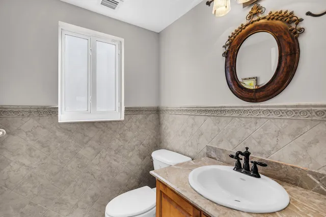 a bathroom with a toilet sink a mirror and vanity