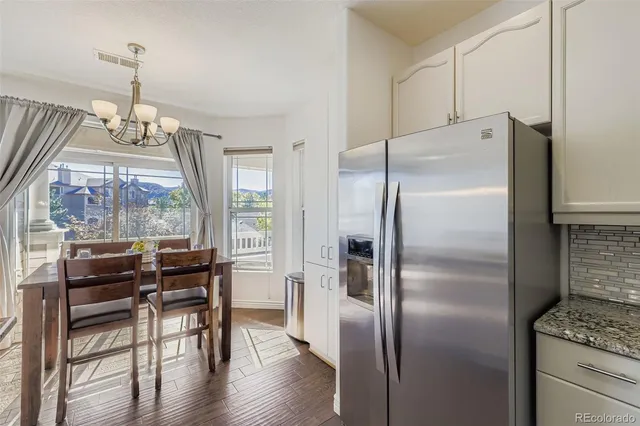 a kitchen with stainless steel appliances a refrigerator a stove a table and chairs