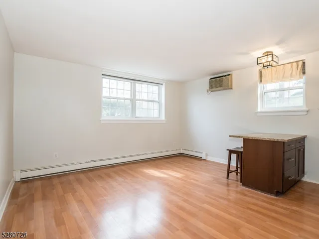 an empty room with wooden floor cabinet and windows