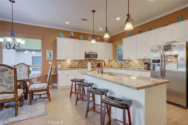 a large kitchen with granite countertop a large white cabinets sink and stainless steel appliances
