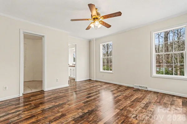 a view of an empty room with a window and wooden floor