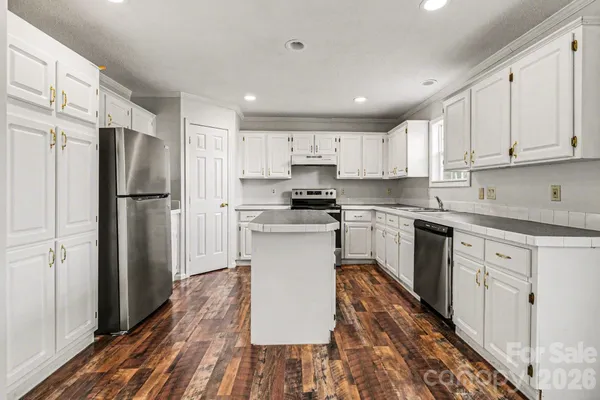 a kitchen with granite countertop a refrigerator stove top oven and cabinets