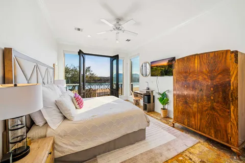 a bedroom with a bed flat screen tv and a large window with the outer view