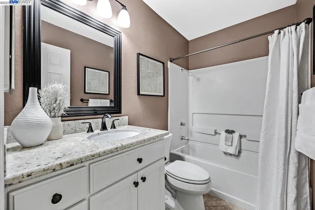 a bathroom with a granite countertop sink mirror vanity and toilet