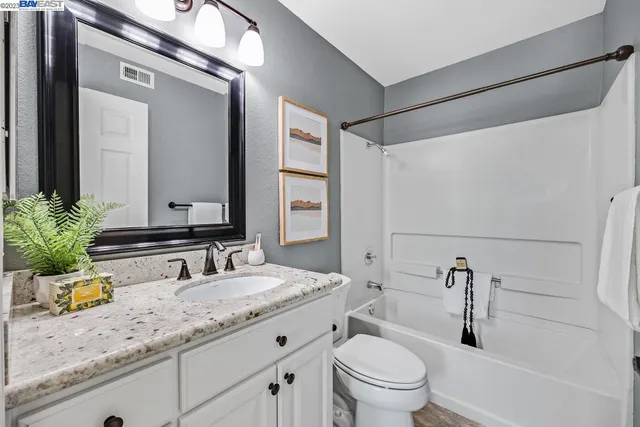 a bathroom with a granite countertop sink a toilet a mirror and shower